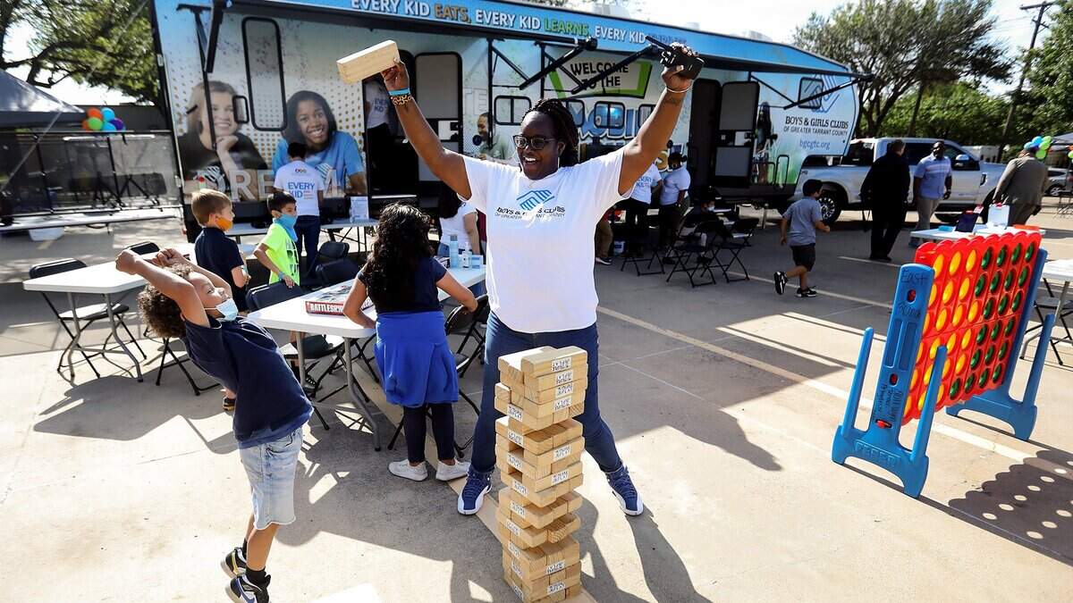 Shakia Jackson-Williams, assistant manager of the East Side Boys & Girls Club, celebrates a successful pull of a giant Jenga block with Boys & Girls Club member Aiden, 7, during an unveiling of the new Mobile Clubhouse Experience in 2021 in Fort Worth. The Mobile Clubhouse is composed of a fleet of vehicles, including the flagship RV, that can be unpacked to bring services, as seen, directly to communities. Shakia Jackson-Williams, assistant manager of the East Side Boys & Girls Club, celebrates a successful pull of a giant Jenga block with Boys & Girls Club member Aiden, 7, during an unveiling of the new Mobile Clubhouse Experience in 2021 in Fort Worth. The Mobile Clubhouse is composed of a fleet of vehicles, including the flagship RV, that can be unpacked to bring services, as seen, directly to communities.